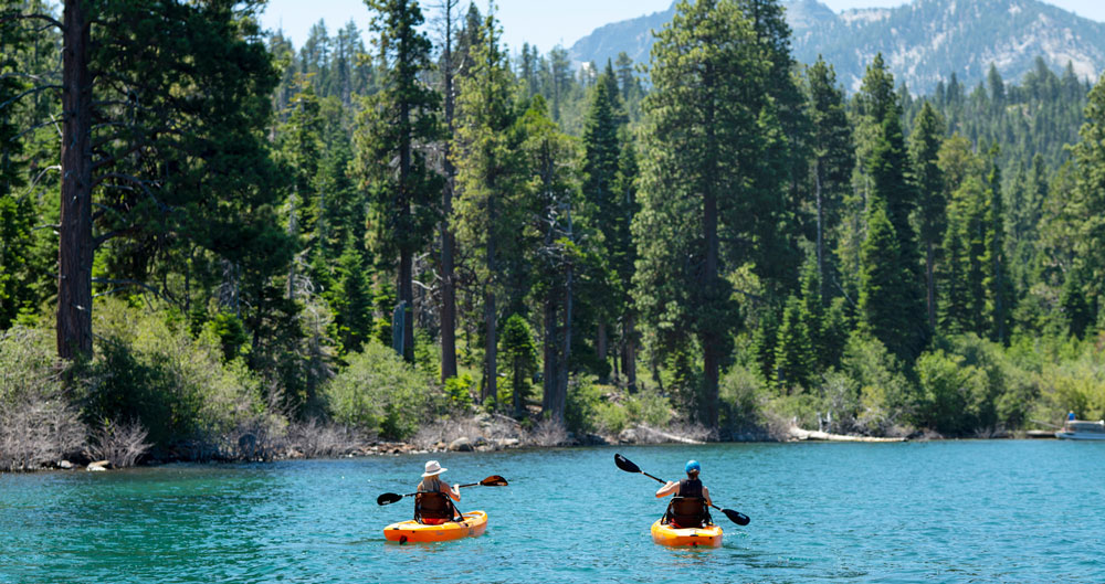 2 kayakers paddling along the shore of lake tahoe