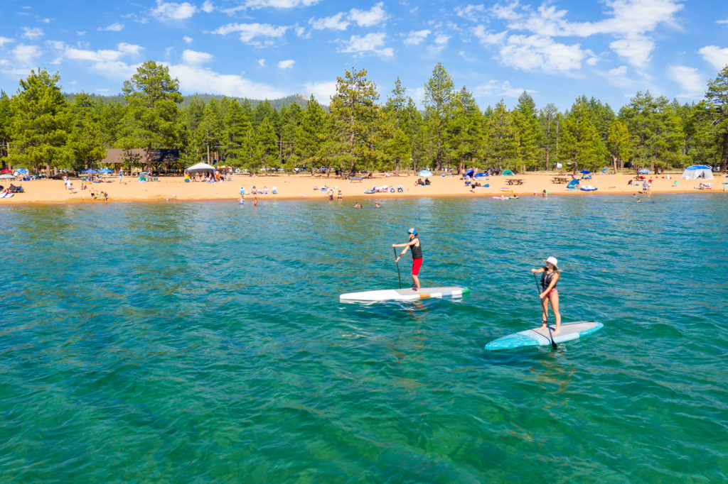 two people at Nevada Beach enjoying paddleboarding Tahoe